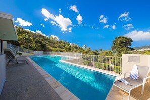 A swimming pool with a white fence, lounge chairs, and a staircase leading to a building. - Tulip Oak - Airlie Beach (Airlie Beach)
