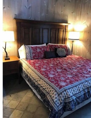 Cozy retreat with a traditional bed and patterned bedspread, accompanied by two bedside lamps.