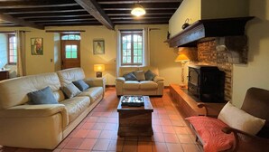 A cozy living room with two sofas, a fireplace, and a tiled floor. - Aguerre - Lichos - Gîte (LICHOS)