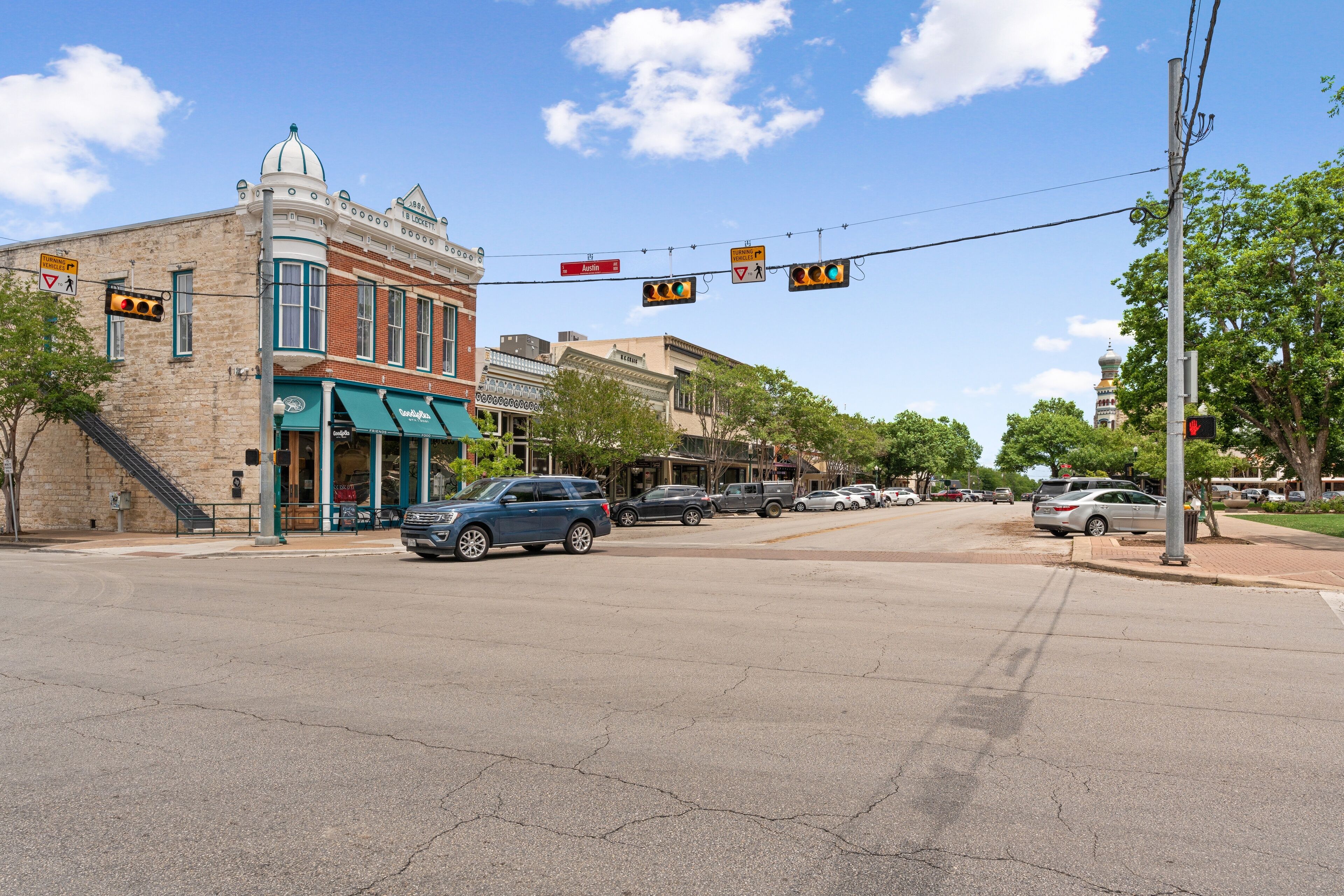 A street intersection with buildings, traffic lights, and cars.