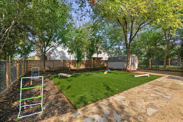 A backyard with a well-maintained lawn, a metal climbing structure, and a small shed.