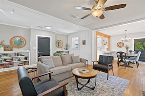 A modern living room with a sofa, armchairs, a coffee table, and a ceiling fan.