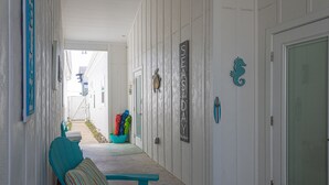 A hallway with a teal chair and bench, a door labeled "SEASIDE," and a seahorse decoration. - PB220 Community Pool, Parking for 2 (Port Aransas)