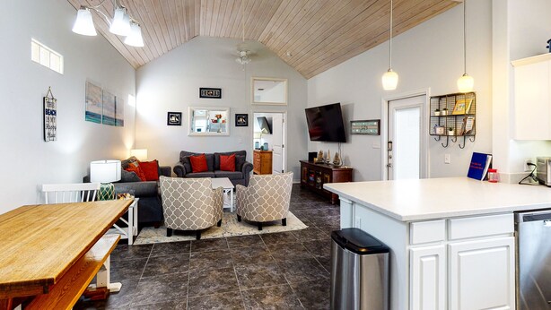 A spacious living area with a sofa, ottoman, and a dining table. - PB220 Community Pool, Parking for 2 (Port Aransas)