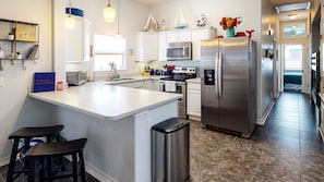 A modern kitchen with white cabinets, stainless steel appliances, and a central island.