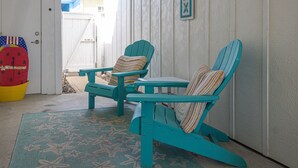 Two turquoise Adirondack chairs with striped pillows, a small table, and a starfish-patterned mat on a porch. - PB220 Community Pool, Parking for 2 (Port Aransas)