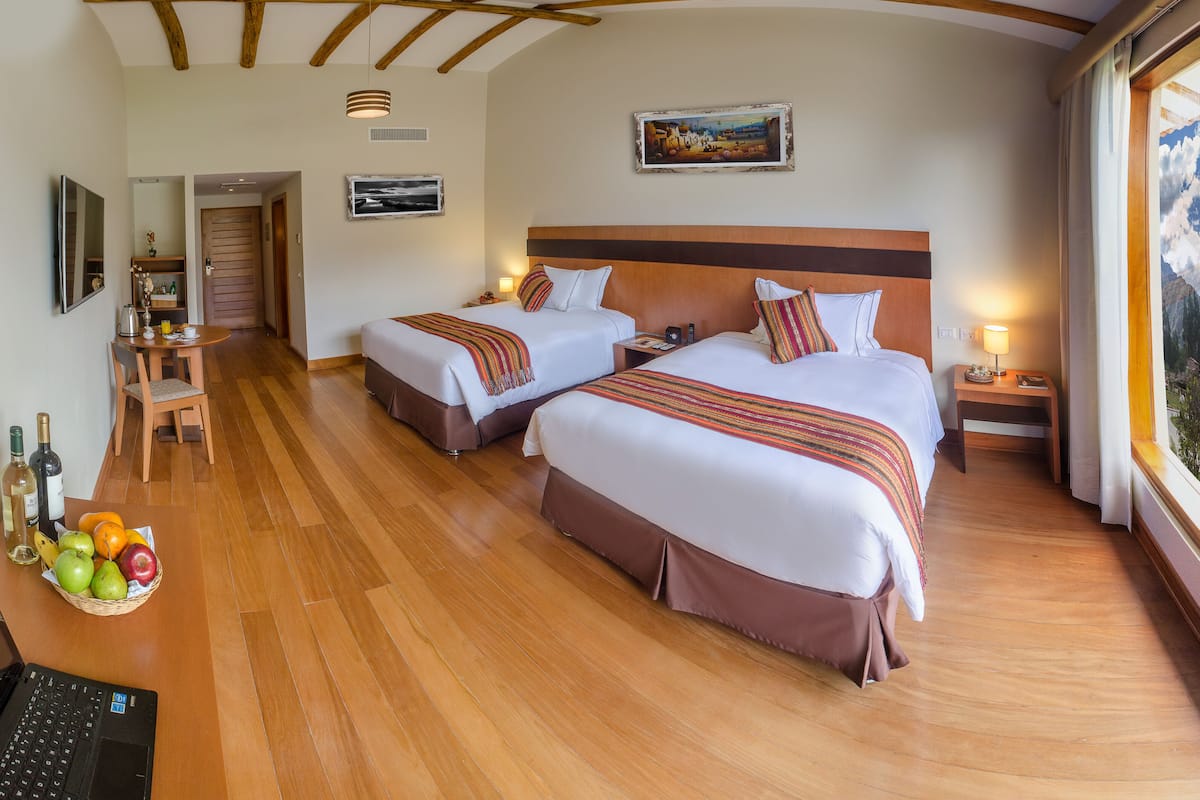 Une chambre d’hôtel avec deux lits, un coin repas, un ordinateur portable et une vue sur les montagnes.