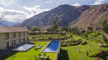 Una piscina al aire libre, sombrillas, sillones reclinables de piscina
