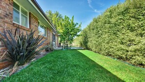 Une pelouse bien entretenue, un bâtiment en briques doté de fenêtres et une haie dense.