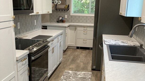 A modern kitchen with white cabinetry, stainless steel appliances, and a marble-patterned rug. - Downtown at your Doorstep (Anchorage)