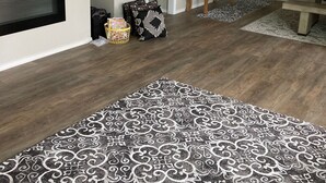 A modern living room with a flat-screen TV, fireplace, patterned rug, and a 'Welcome' sign. - Downtown at your Doorstep (Anchorage)