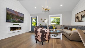 Una sala de estar amplia con chimenea, un cuadro grande y un rincón de descanso acogedor con sofá y sillones.