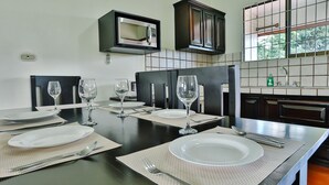 A dining area with a black table set for four, including plates, cutlery, and wine glasses. - Apartment 10: Condos Vista al Volcan - Second Floor (La Fortuna)