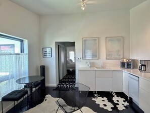 A modern kitchen with a dining area, a black and white patterned rug, and a view through an open door. - The No. 3: modern, bright, renovated, downtown condo with outdoor lounge space (Marfa)