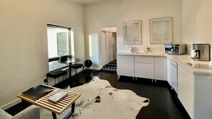 A compact kitchen with a dining area, a white cowhide rug, and a coffee machine. - The No. 3: modern, bright, renovated, dwtn condo w/ outdoor lounge space (Marfa)