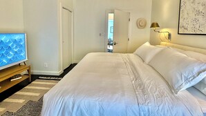 A hotel room with a large bed, a bedside table, a lamp, a map on the wall, and a view of the hallway. - The No. 3: modern, bright, renovated, dwtn condo w/ outdoor lounge space (Marfa)
