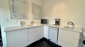 A modern kitchen with white cabinetry, a built-in oven, a coffee maker, and a kettle on the countertop. - The No. 3: modern, bright, renovated, dwtn condo w/ outdoor lounge space (Marfa)