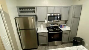 A compact kitchen with stainless steel appliances, including a refrigerator, microwave, and stove. - Large 1 Bedroom Apartment on Westheimer Road (Houston)