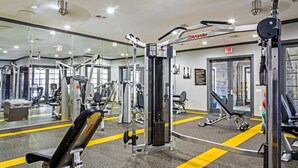 A gym with various exercise machines, a mirrored wall, and a fitness center sign. - Large 1 Bedroom Apartment on Westheimer Road (Houston)