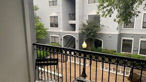 A balcony with a grill, a chair, and a suitcase. - Large 1 Bedroom Apartment on Westheimer Road (Houston)