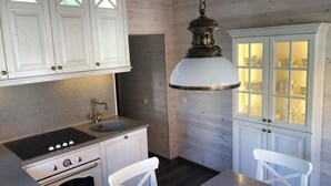 A kitchen with white cabinets, a stove, a sink, and a hanging light fixture.