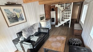 A spacious living room with a black leather sofa, a wooden coffee table, and a staircase leading to another level.