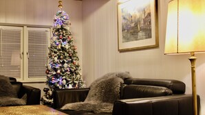 A living room with a Christmas tree, a framed picture on the wall, and a lamp.