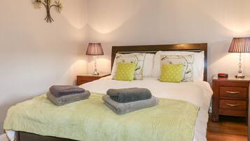 A neatly made bed with two pillows, a bedside table with a lamp, and a wall decoration.