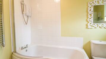 A bathroom with a white bathtub, a toilet, and a shower with a handheld showerhead.