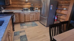 A kitchen with wooden cabinets, a refrigerator, a microwave, and a coffee maker.
