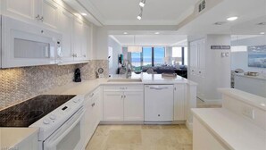 Una cocina moderna con armarios blancos, horno empotrado y una isla grande con fregadero.