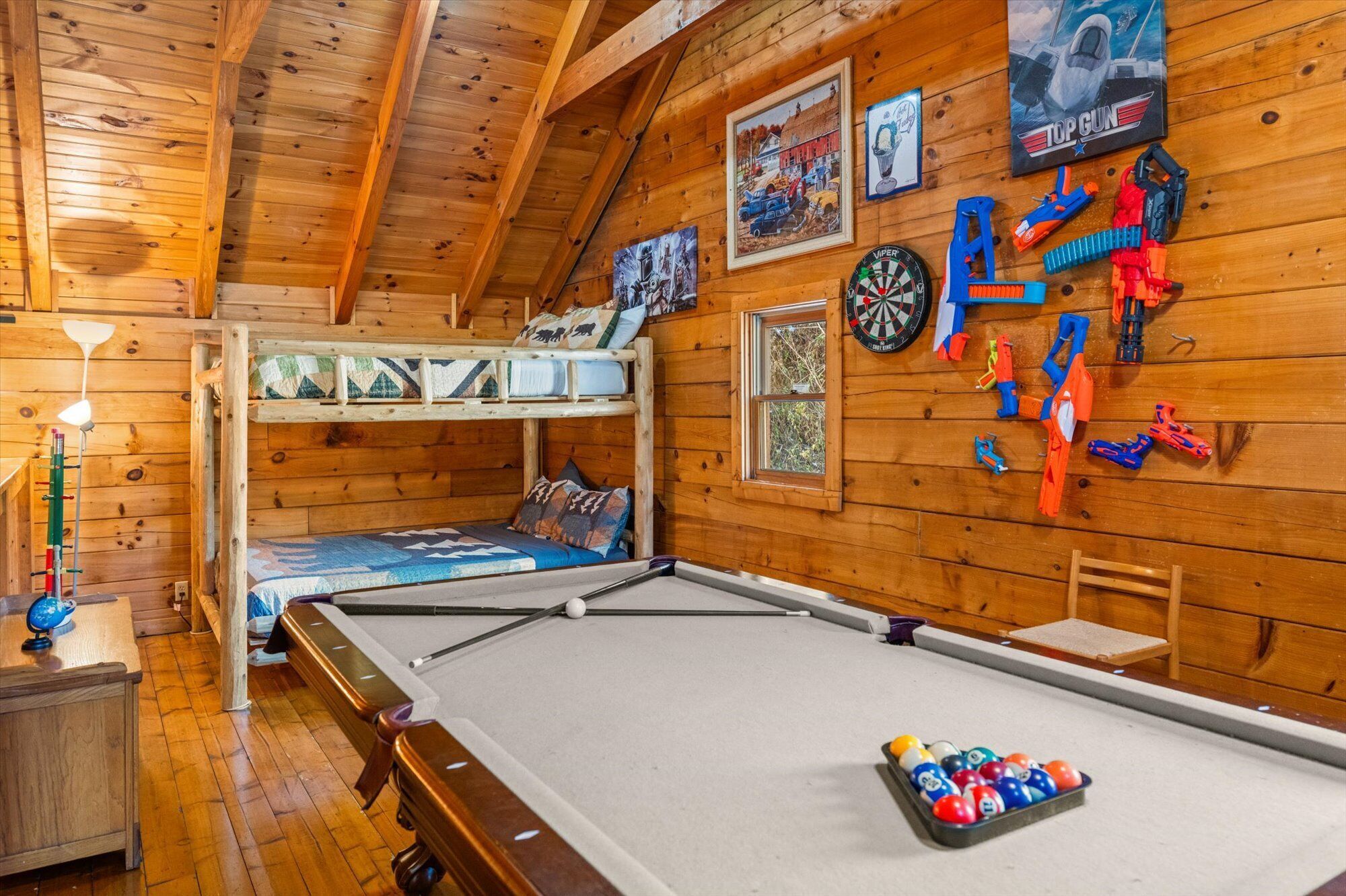 Une cabane en bois chaleureuse, dotée de lits superposés, d’une table de billard et de divers jouets et objets de décoration.