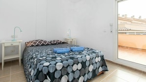 Ein Schlafzimmer mit einem Bett, zwei Nachttischen, einem Fenster und Blick auf Gebäude.