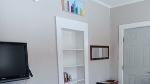 Ein Wohnzimmer mit Kamin, Fernseher, Bücherregal, einer Tür und einem Teppich.