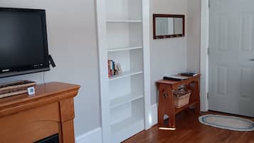 A living room with a fireplace, a television, a bookshelf, a door, and a rug.