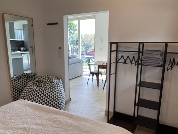 A bedroom with a bed, a patterned bean bag, a wardrobe, and a balcony with a table and chairs. - Bundeena Base Cottage (BUNDEENA)