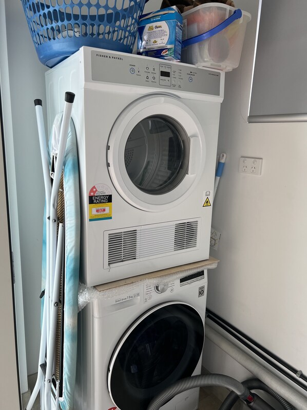 Un appareil combiné lave-linge et sèche-linge, avec un panier bleu et un compartiment à lessive placés sur le dessus.
