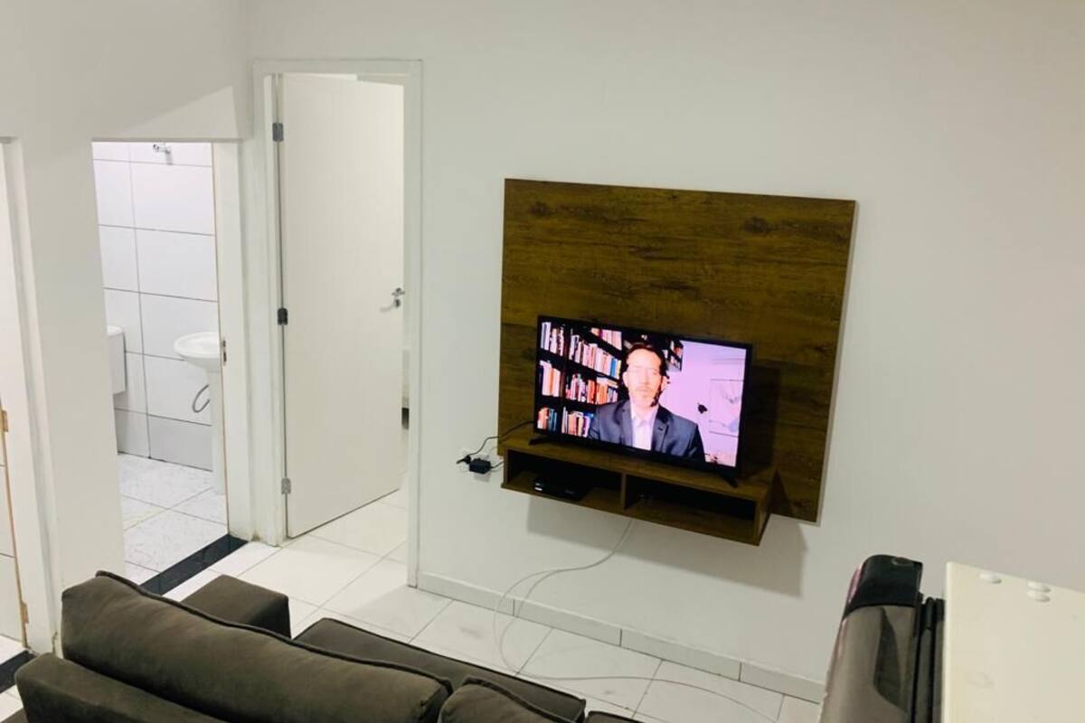 Una sala de estar con un televisor montado, un sofá y una puerta que da a un baño.
