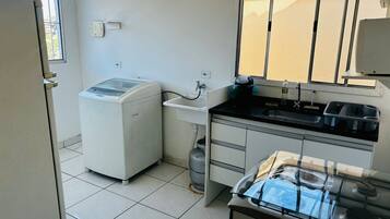 A compact kitchen with a washing machine, a sink, and a gas stove.