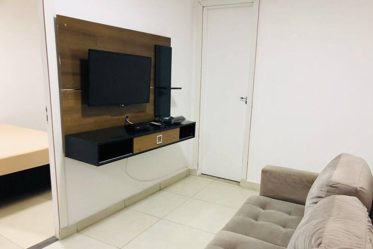 Un salón con un sofá color beige, un televisor montado y una pared de madera decorativa.