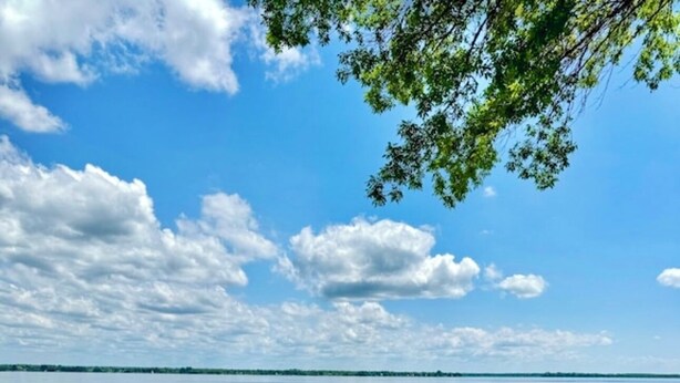 A grassy lakeside area with a dock, a kayak, and a chair.