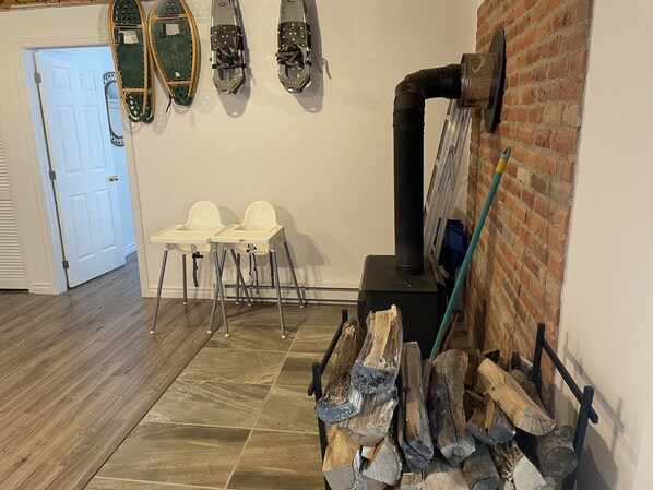 A room with a fireplace, two white high chairs, a door, and a brick wall. - Grandes-Piles cottage (Grandes-Piles)