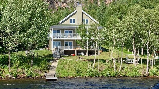 Una casa de dues plantes amb un balcó, situada vora un llac amb un moll que hi desemboça.