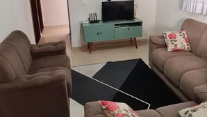 A living room with two brown sofas, a teal entertainment unit with a TV, and a ceiling fan. - Wonderful property 3 min away. Thermal Baths - 4 bedrooms - POOL 5 x 3 - Wi-Fi - complete (SP)
