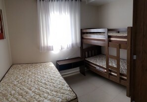 Un dormitorio con una cama individual, una litera y un escritorio pequeño.