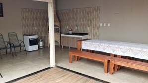 A compact living space with a kitchenette, a dining table with a lace tablecloth, a bench, and a seating area with metal chairs. - Wonderful property 3 min away. Thermal Baths - 4 bedrooms - POOL 5 x 3 - Wi-Fi - complete (SP)