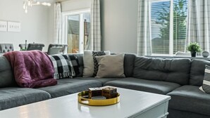 Un salón moderno con un sofá gris, una mesa de centro blanca y una bandeja amarilla con bloques de madera.
