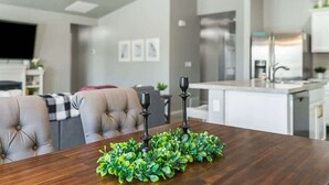 Un comedor moderno con una mesa de madera, plantas verdes y candelabros negros.