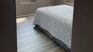 Une chambre à coucher avec un lit, deux fenêtres et un luminaire au plafond.