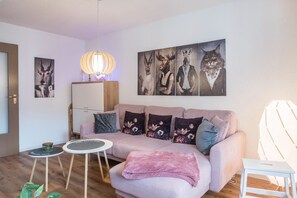 En stue med en sofa, to små borde, en lampe og billeder på væggen.